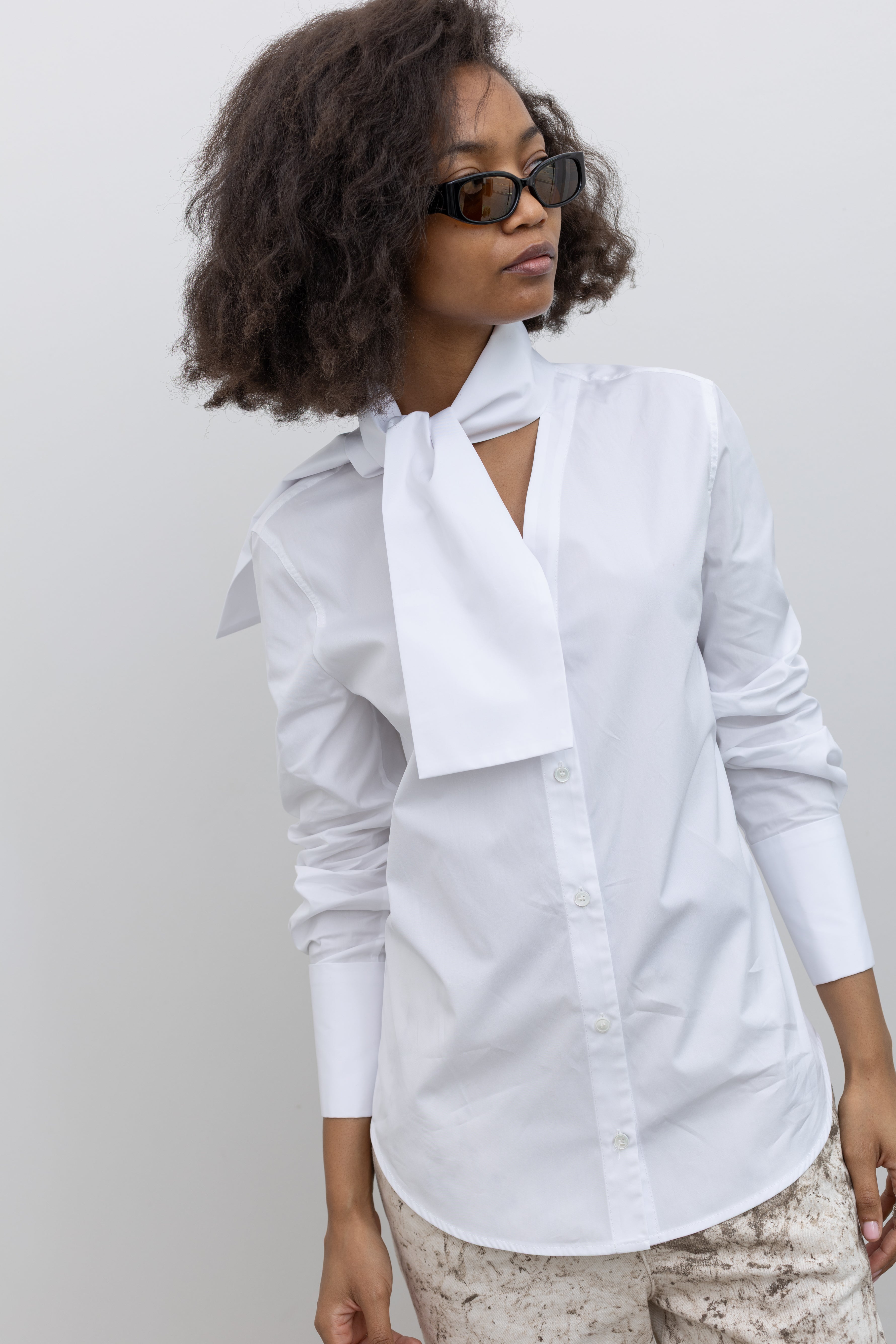 Tela Deanna classic white shirt reimagined with wide cuffs and a refined ascot-style neck tie at alas eius.