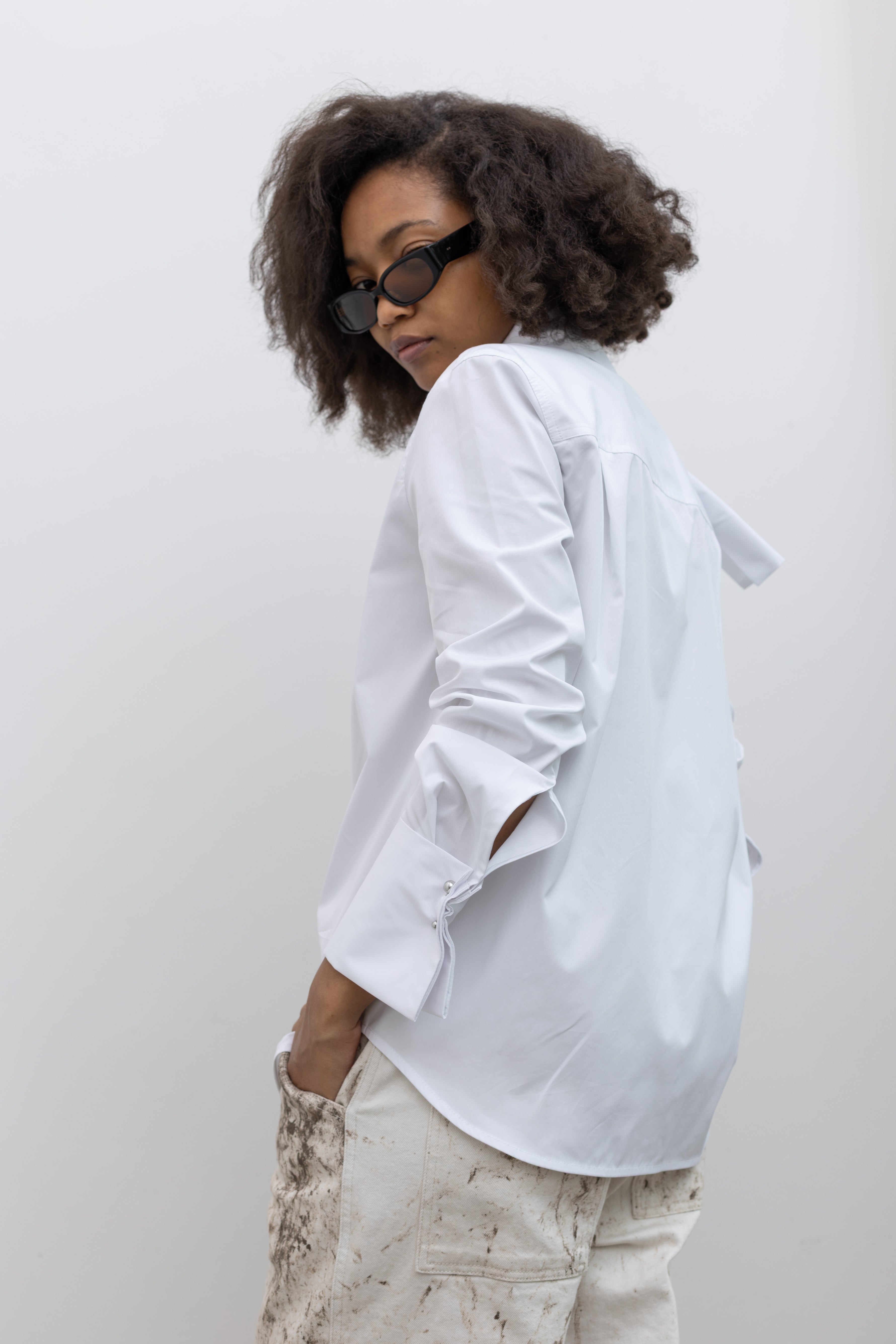 Tela Deanna white shirt designed with wide cuffs, classic tailoring, and an ascot-style neckline at alas eius.