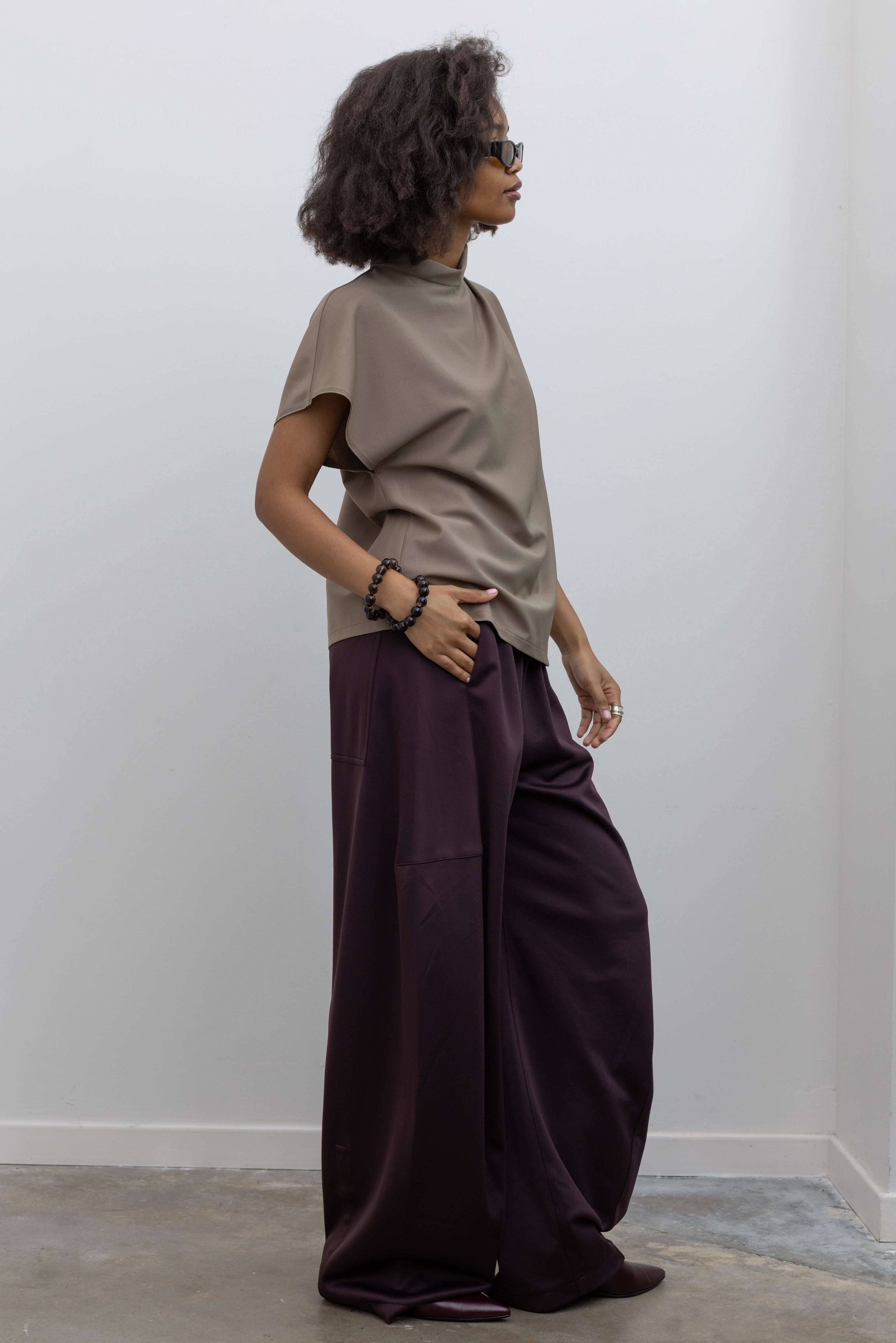 Tela sophisticated wool-blend top with a draped front, high neck, and button closure at the back neckline at alas eius.
