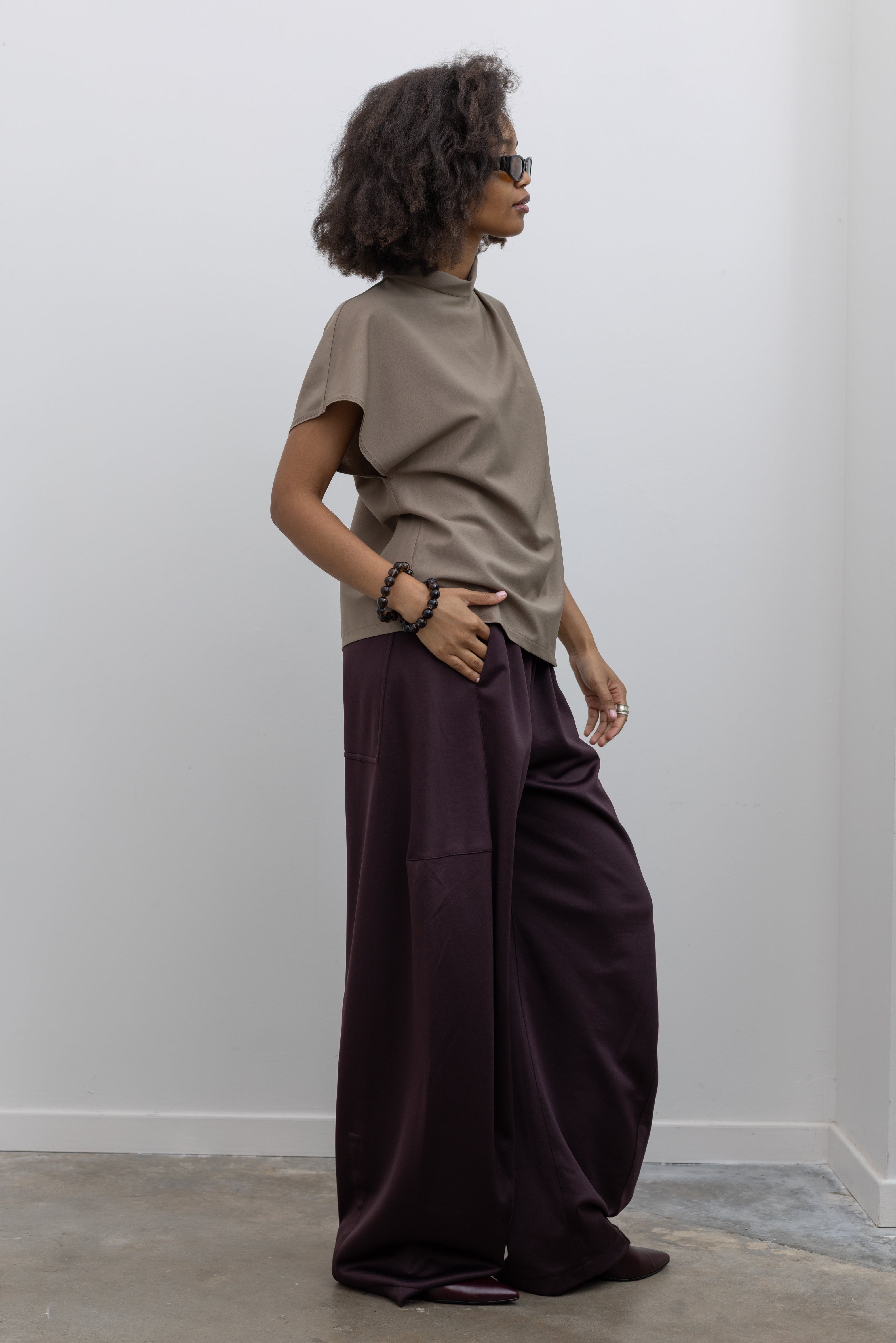 Tela sophisticated wool-blend top with a draped front, high neck, and button closure at the back neckline at alas eius.