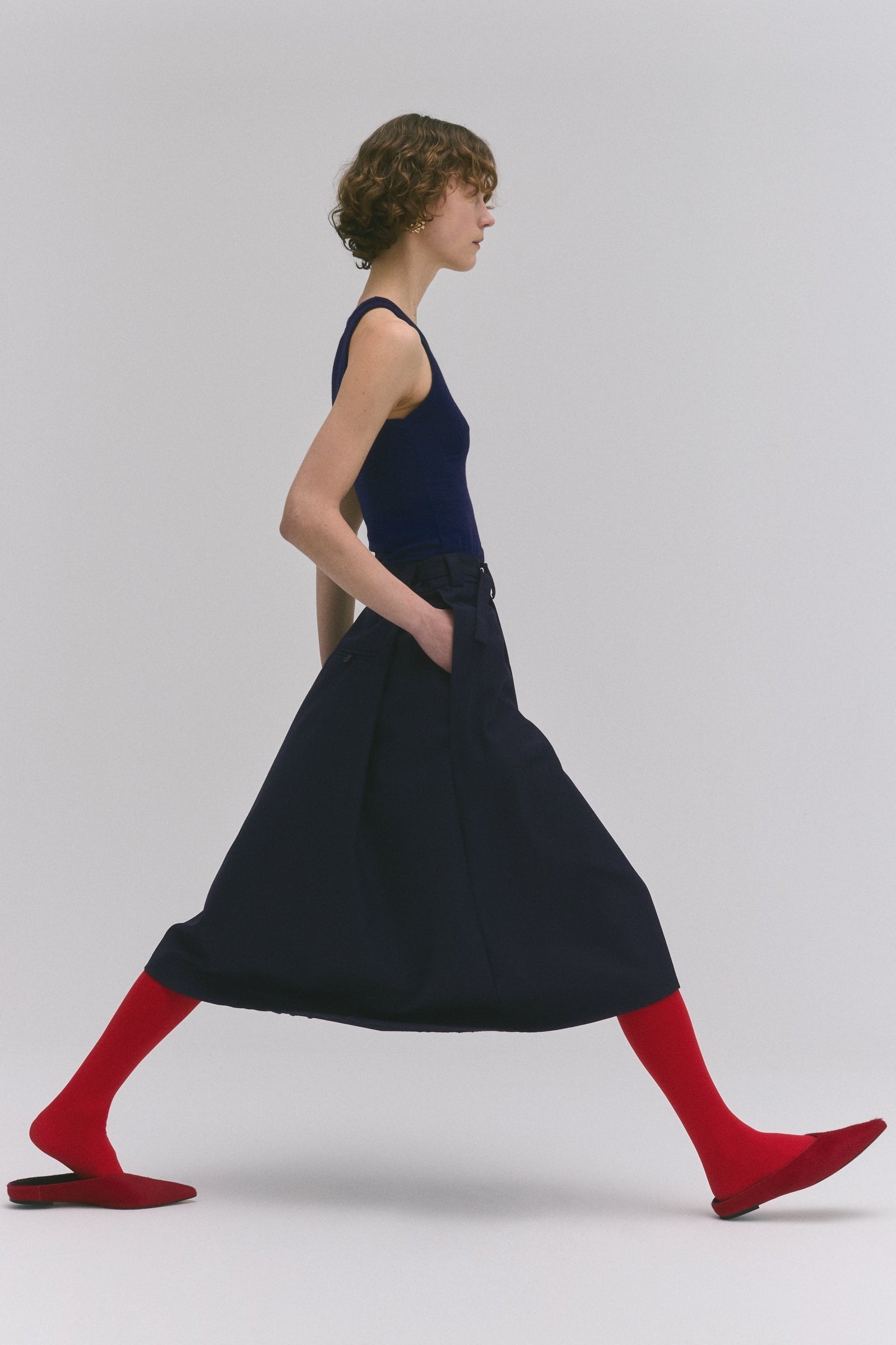 Tela Manami FW26 red pony hair flat mule styled with navy midi skirt and fitted tank top at alas eius