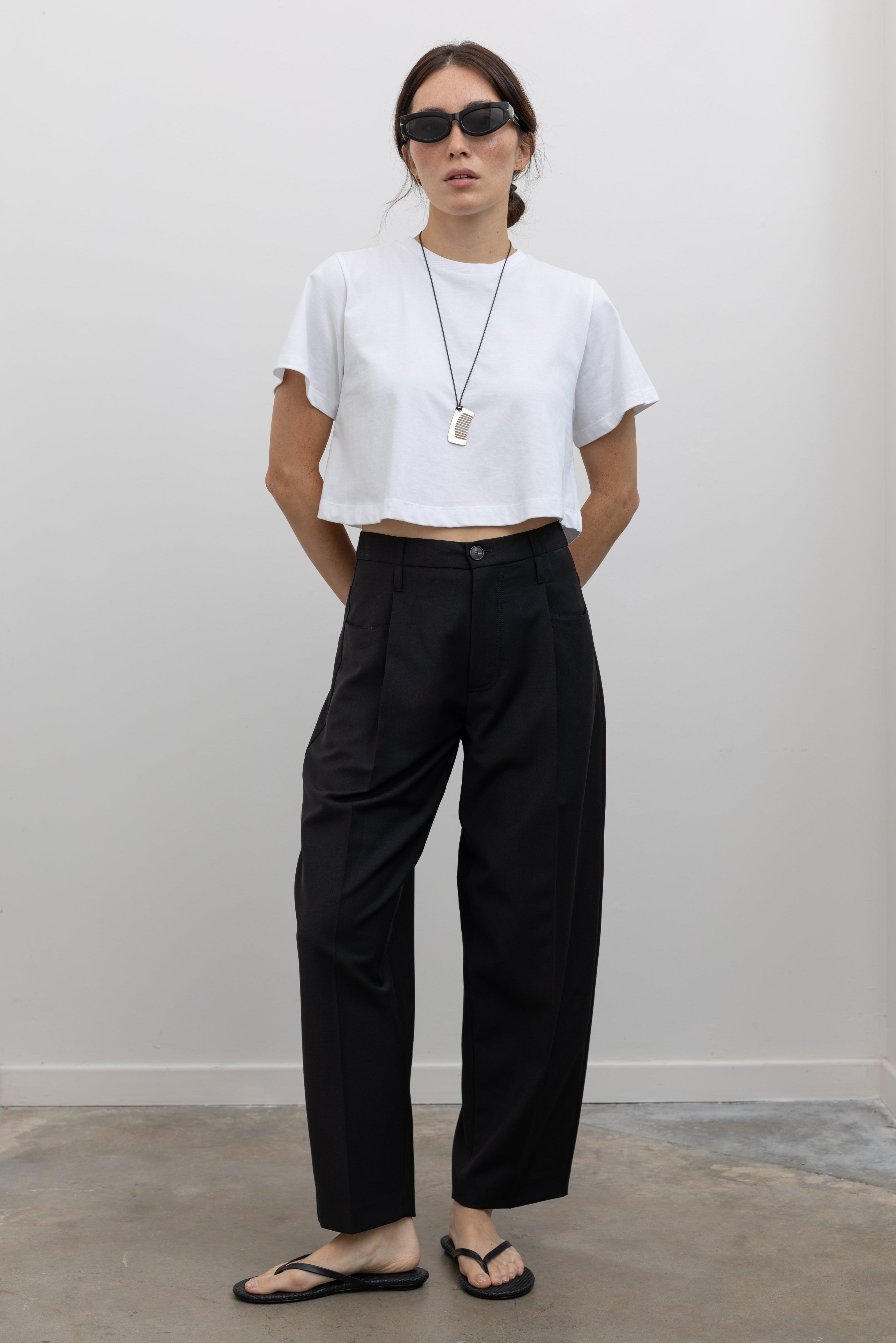 Tela black wool-blend trousers with front pleats and a slightly cropped ankle-length silhouette at alas eius.