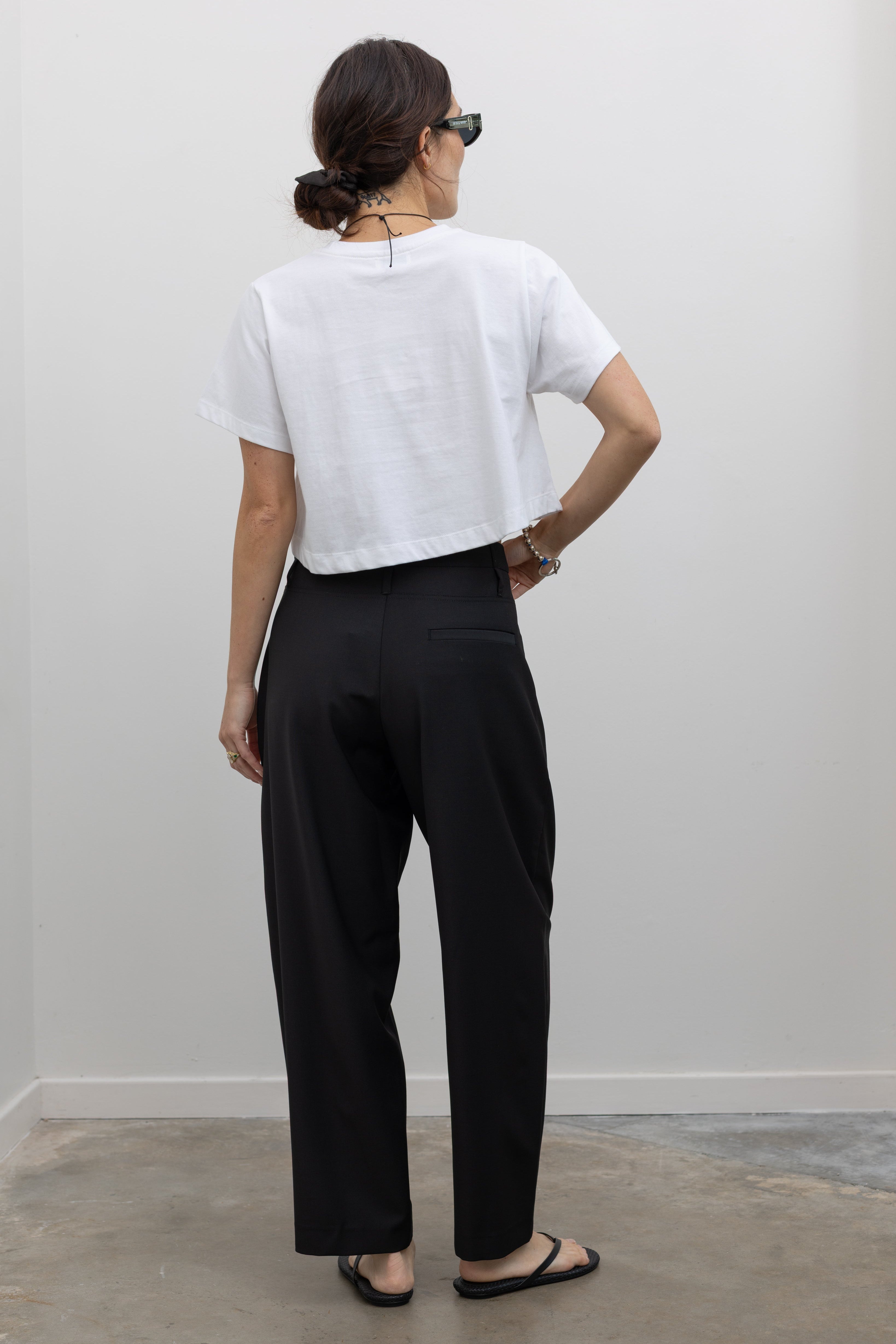 Tela tailored black pant crafted in Italy with elegant pleating and a fluid silhouette at alas eius.